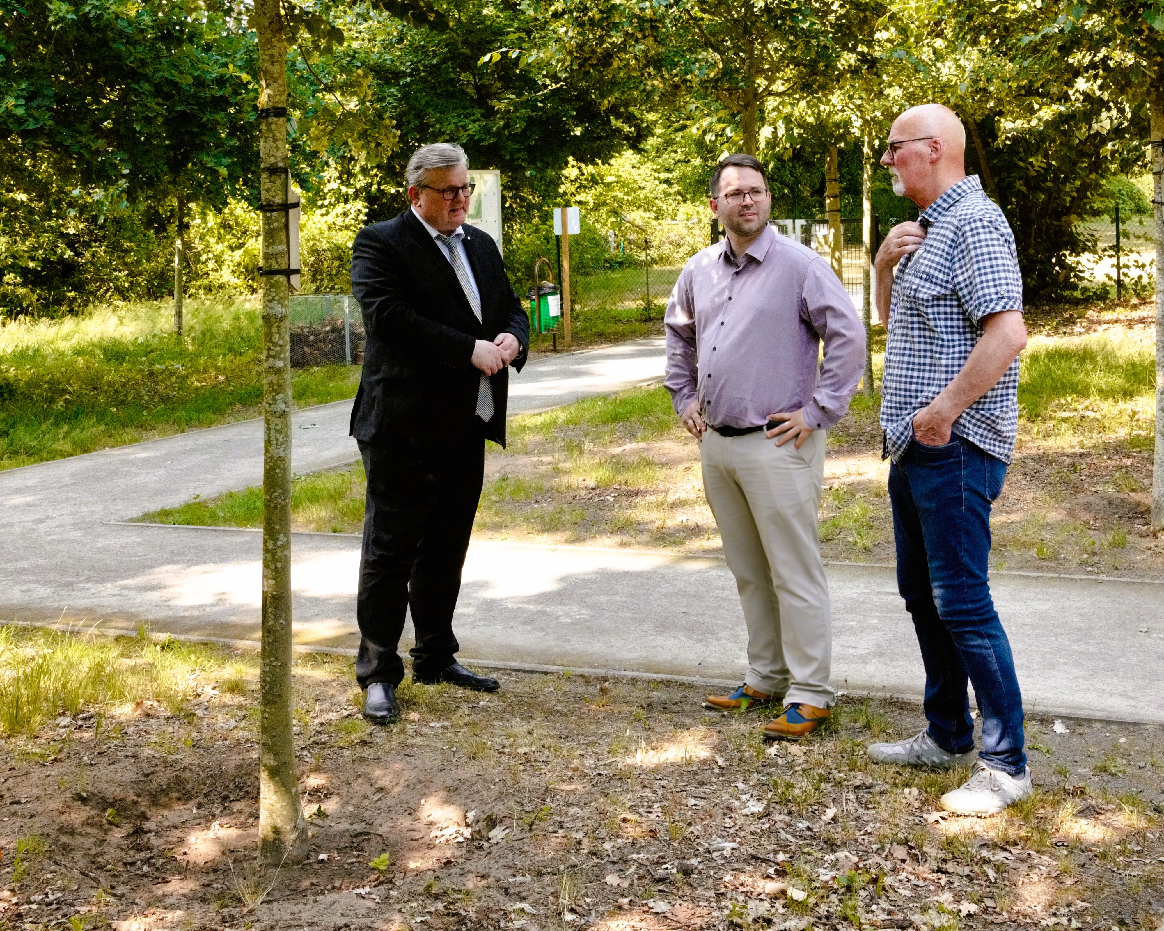 Drei Personen stehen im Bestattungshain Schloß-Ricklingen und unterhalten sich.